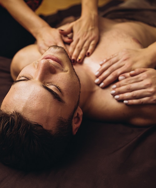 Two therapist giving four hands massage to a man