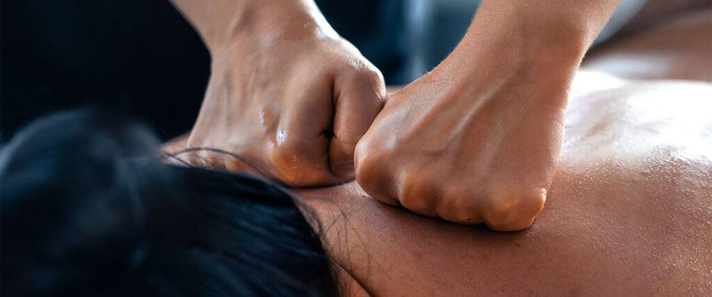A professional massage therapist at Yinyang Spa applying firm pressure with their forearm to a client's back to release chronic muscle knots.