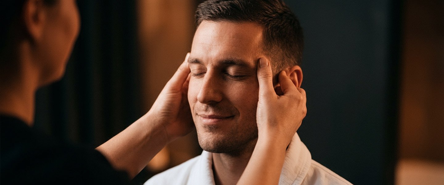 Therapist performing head and temple massage to relieve tension headaches and reduce stress.